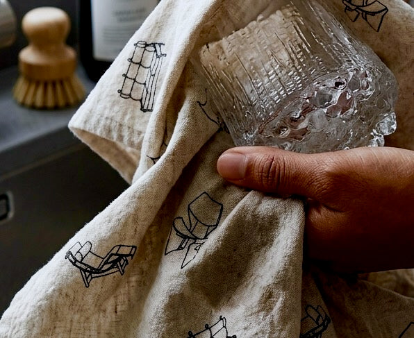 person drying an Ultima Thule Old Fashioned glass with a 20th Century Objects tea towel