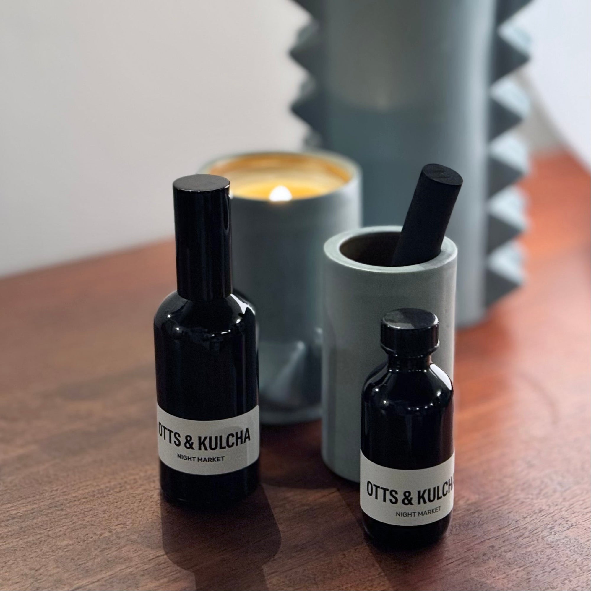 black room spray bottle with black diffuser bottle and pale blue candle burning.