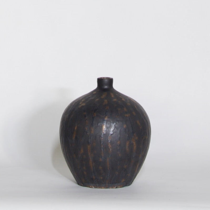 A dark brown ceramic vase with a textured, speckled glaze and a short, narrow neck, photographed against a plain white studio background.