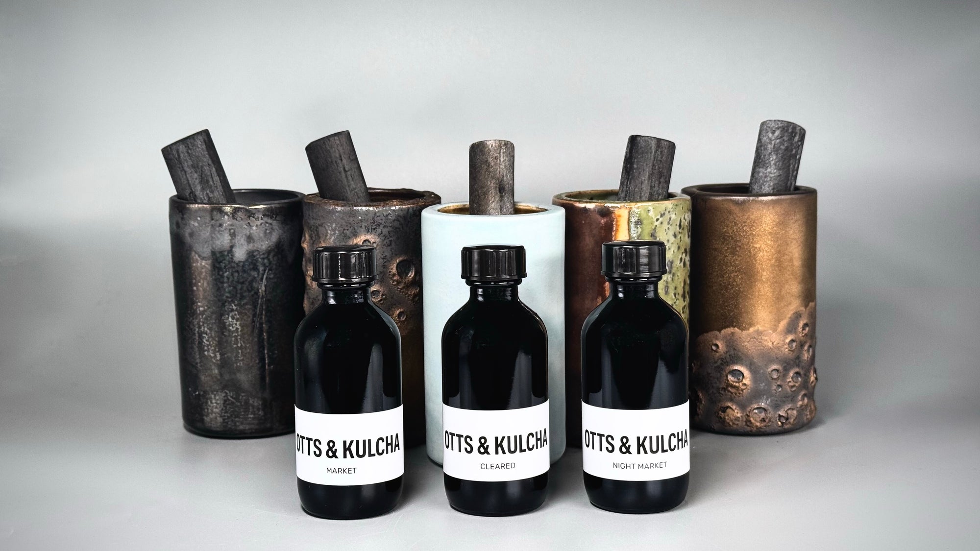 5 ceramic vessels and 3 black bottles with white labels