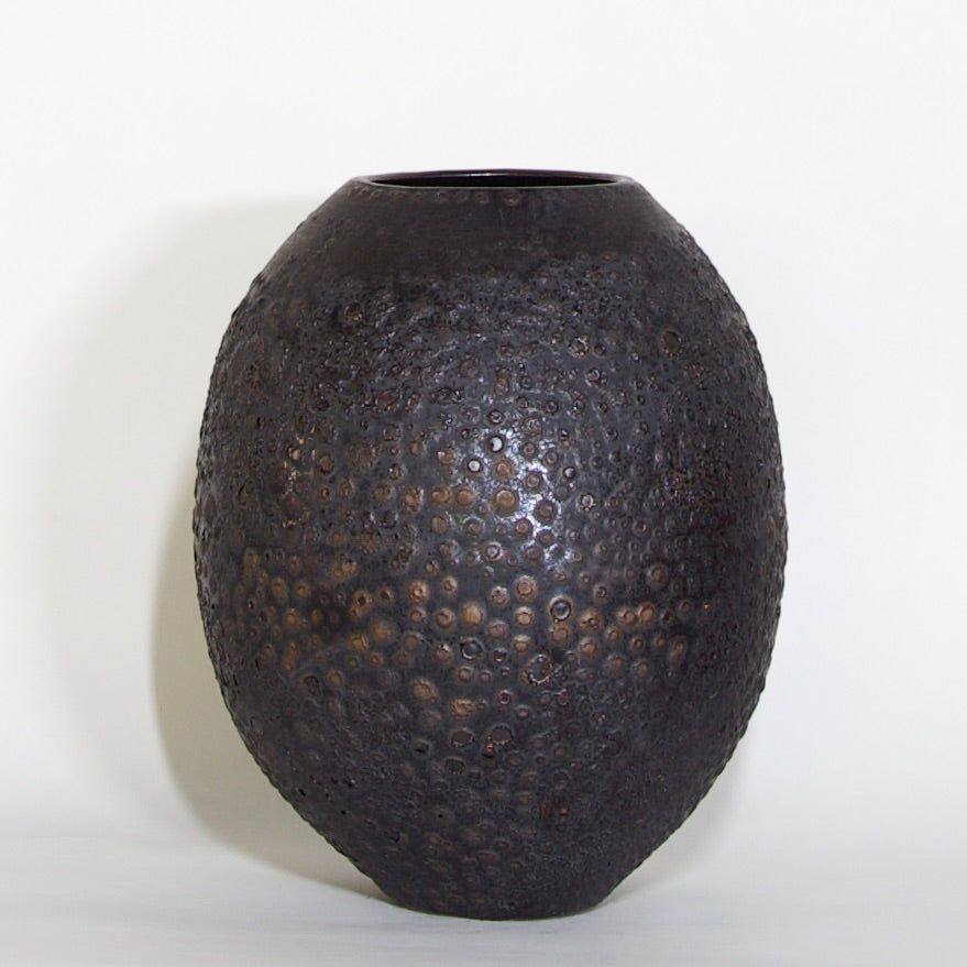 A dark brown textured ceramic vase with a hammered, dimpled surface, photographed against a plain white background.