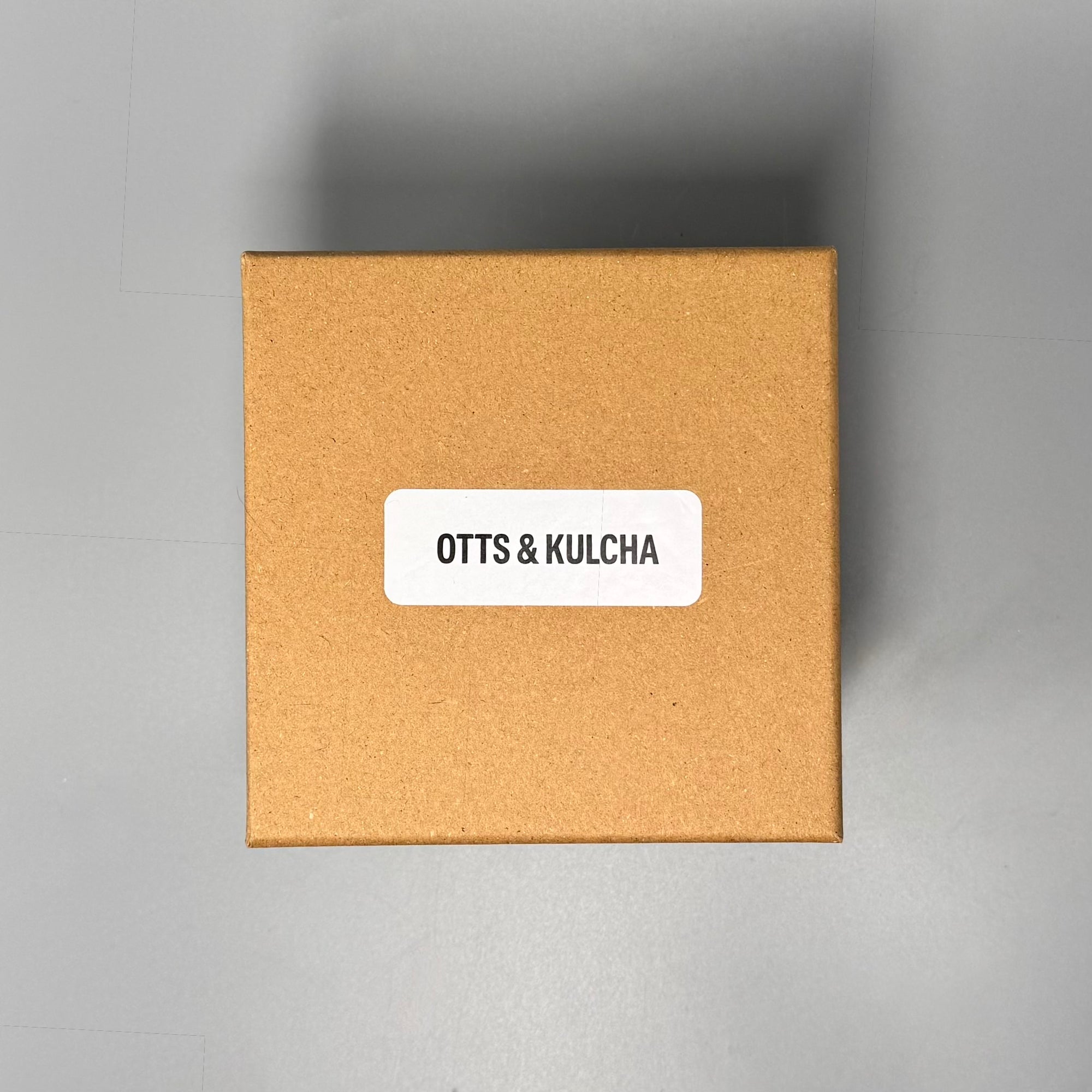 Brown cardboard box with 'OTTS & KULCHA' label on a gray background