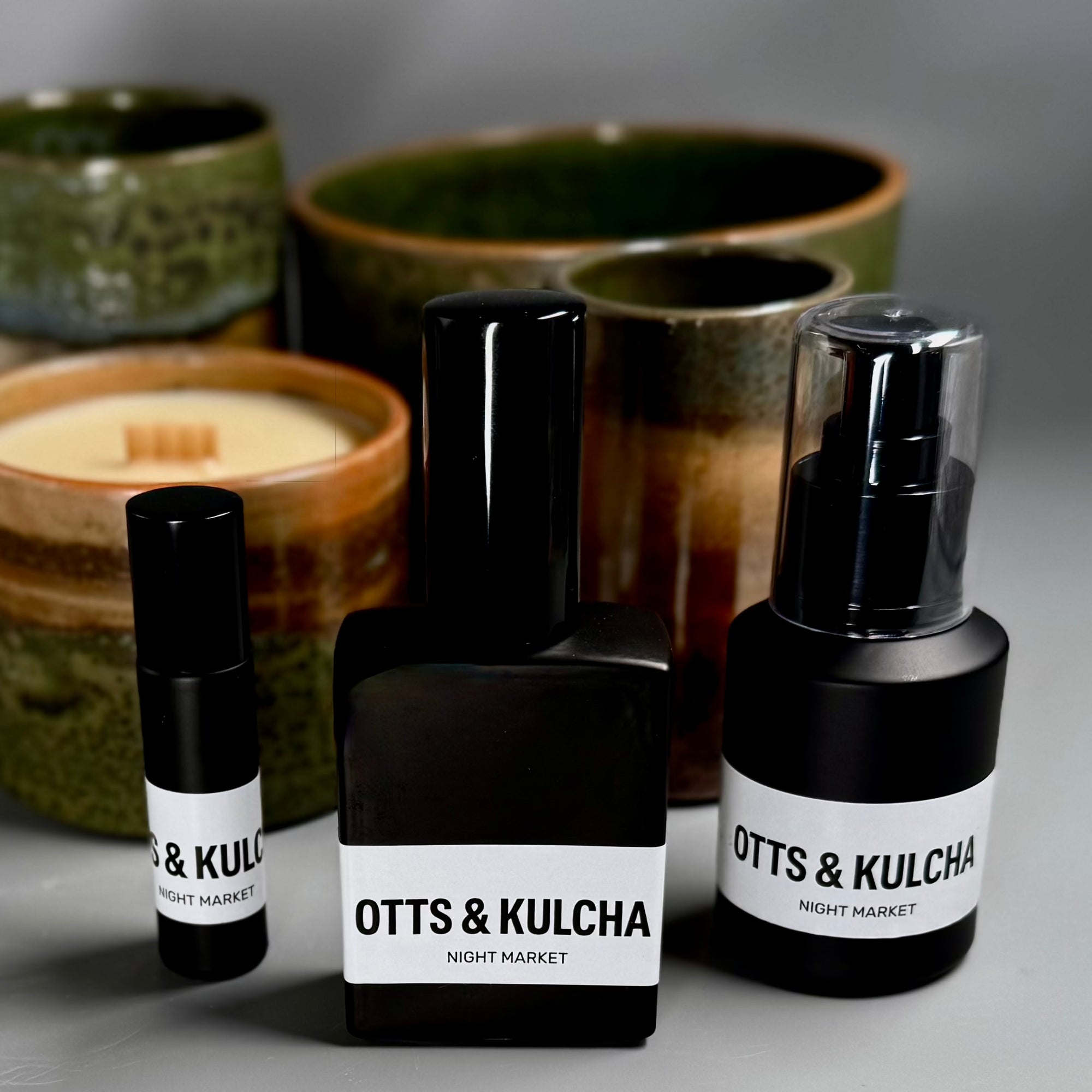 OTTS & KULCHA perfume bottles on a gray surface with ceramic containers in the background