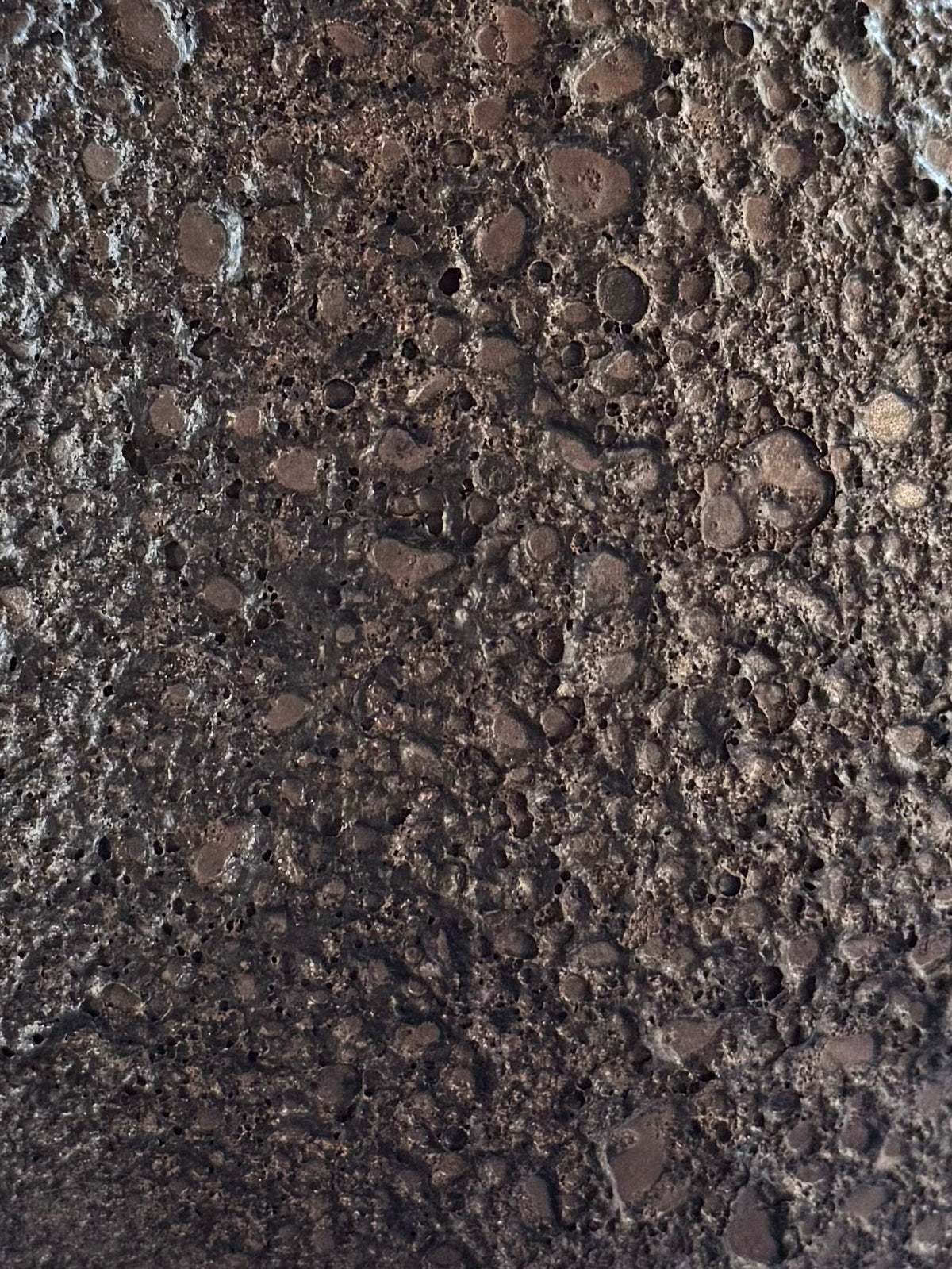 A close-up texture of dark brown rough, granular surface.