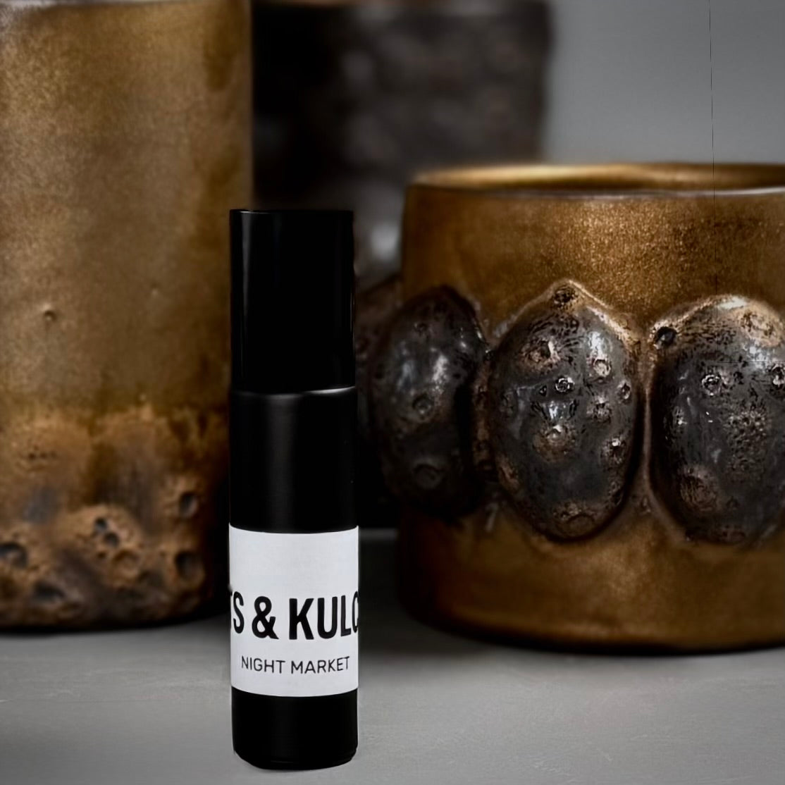 Small black bottle with a white label on a gray surface with ceramic pots in the background