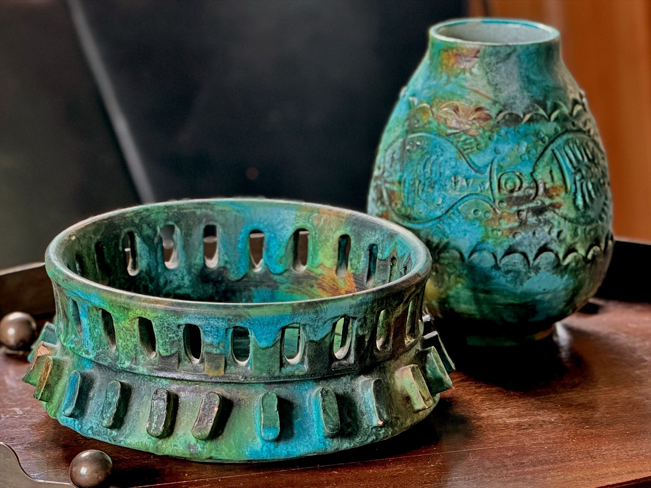 Two ceramic items with green and blue glaze on a wooden surface.