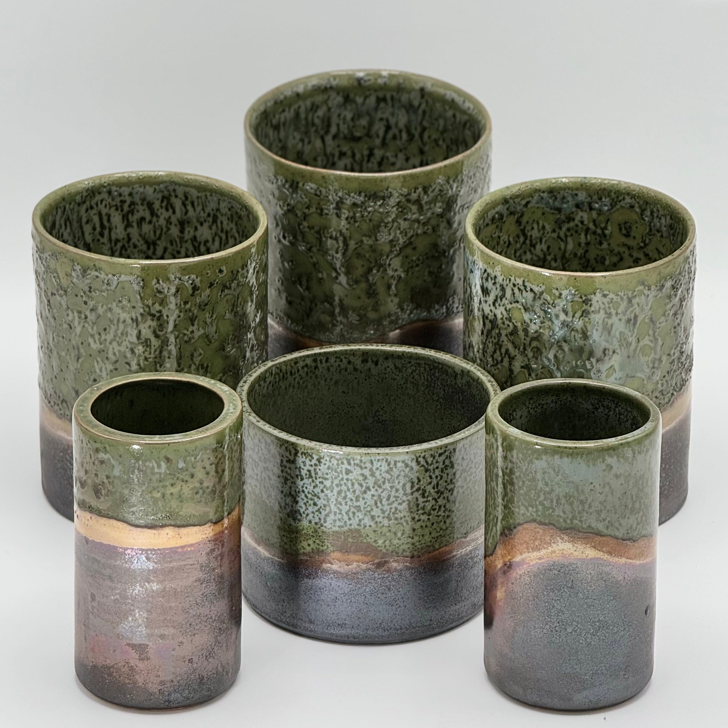 Set of six ceramic tumblers with green and brown glaze on a white background