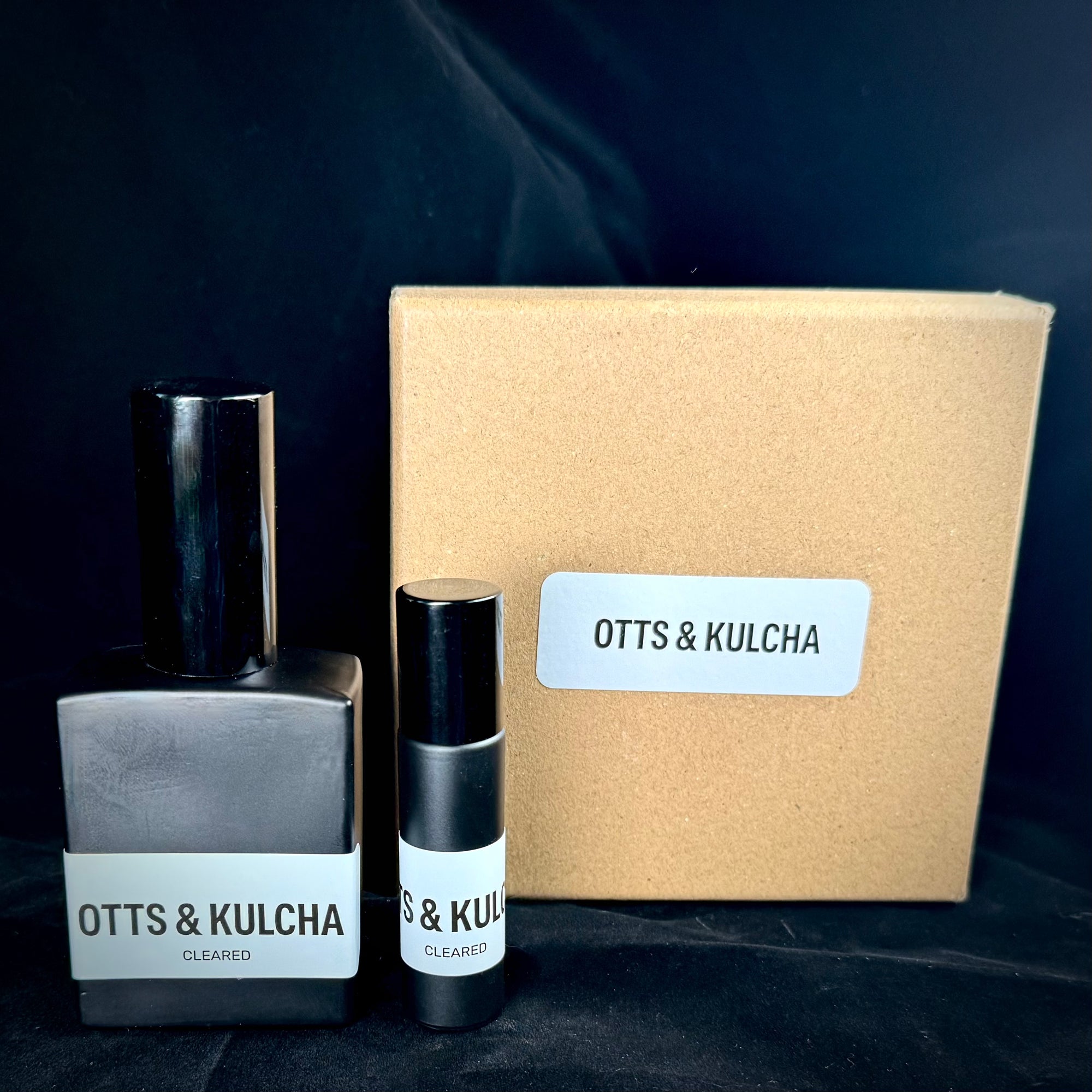 Two bottles of Otts & Kulcha products with a cardboard box on a dark background